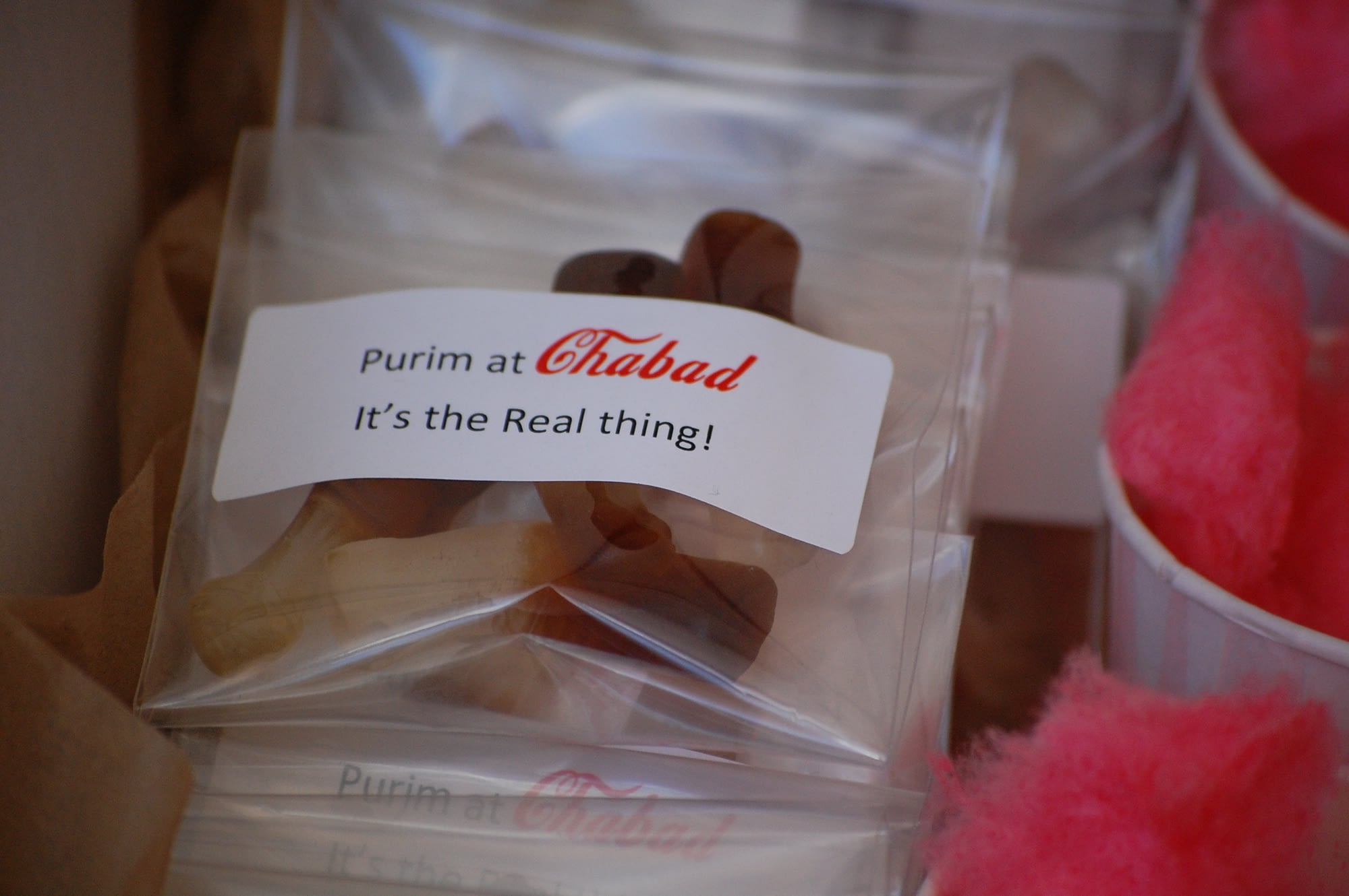 Place a few gummies in a small clear bag and print address lables that say "Purim at Chabad...It's the real thing!".